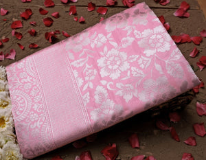 Pink fabric with white floral pattern on a wooden surface with red flower petals