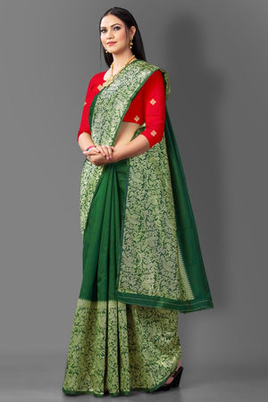 Woman wearing a green and red saree with a plain background