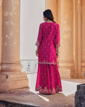 Woman in a pink traditional outfit standing in front of classical architecture.