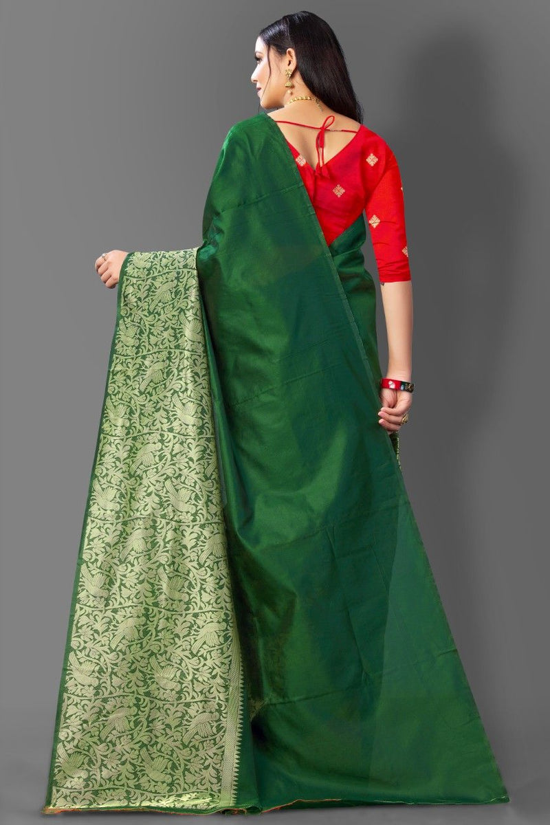 Woman wearing a red blouse with a green saree against a gray background