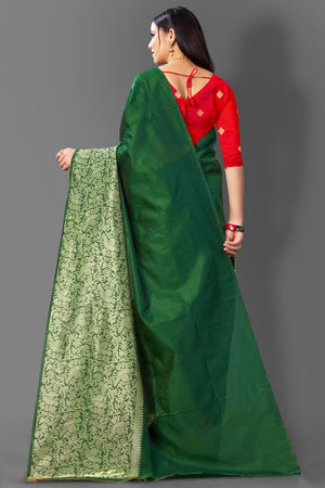Woman wearing a red blouse with a green saree against a gray background