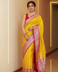 Woman wearing a yellow saree with pink border indoors