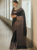 Woman wearing a black and brown saree with a white wall background