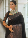Woman wearing a black saree with silver border and jewelry indoors