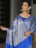 Woman wearing a blue saree with a patterned border against a blurred background