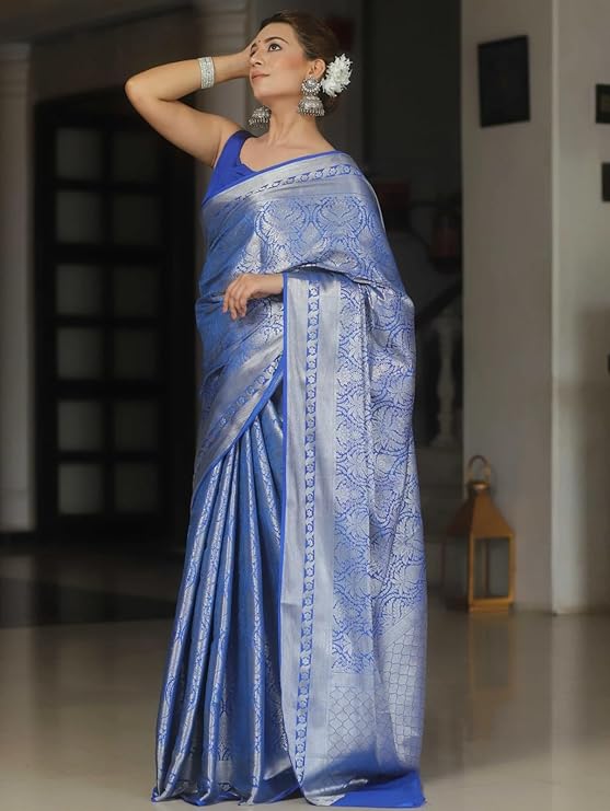Woman wearing a blue saree with white patterns indoors.