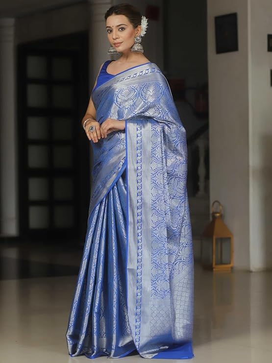 Woman wearing a blue saree with intricate patterns indoors.