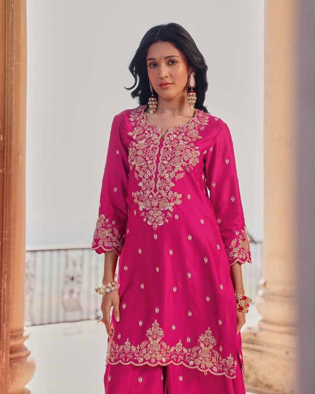 Woman wearing a pink embroidered traditional outfit with a white background