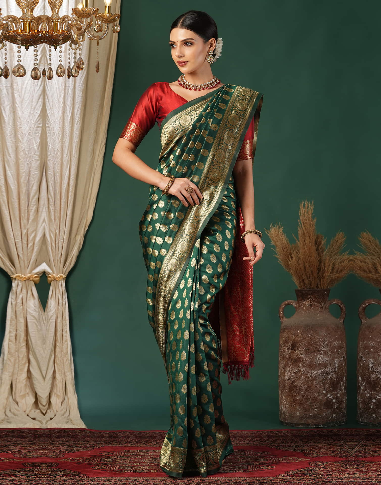 Woman in a green and gold saree with a red blouse against a decorative background