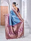 Woman holding a blue and brown saree in a bright room