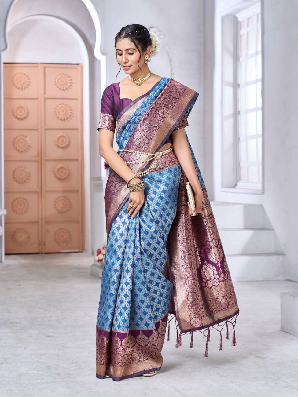 Woman wearing a blue and purple saree in a white room