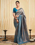 Woman wearing a gray and blue saree with a decorative background