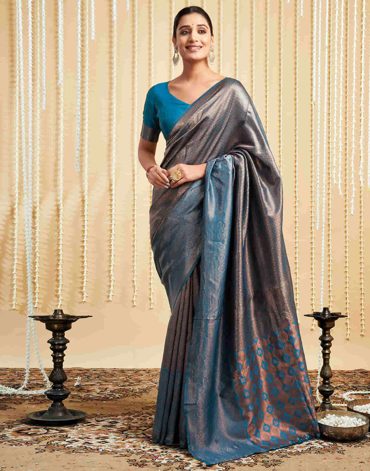Woman wearing a gray saree with a blue blouse against a decorative background