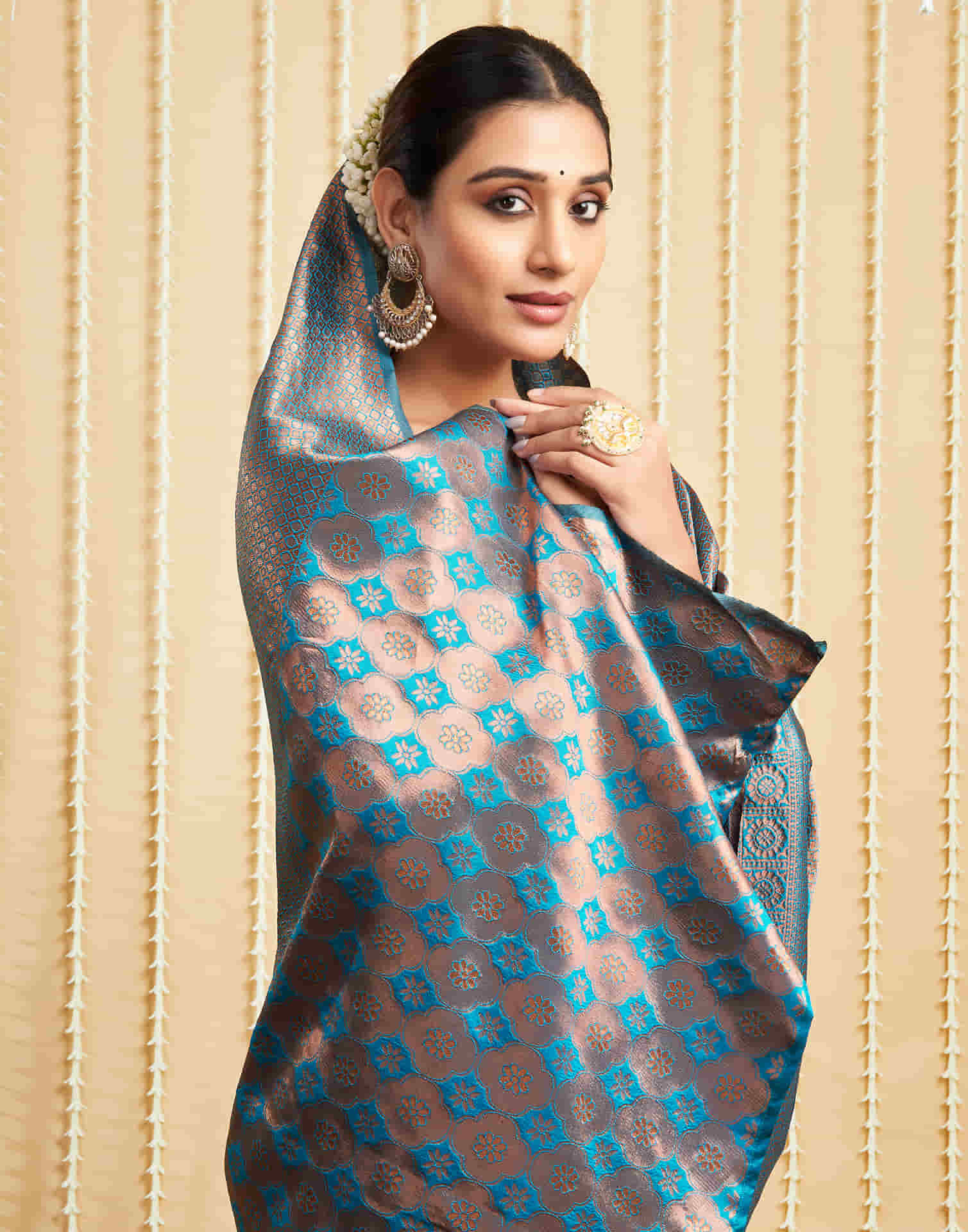 Woman wearing a patterned saree with a beige background
