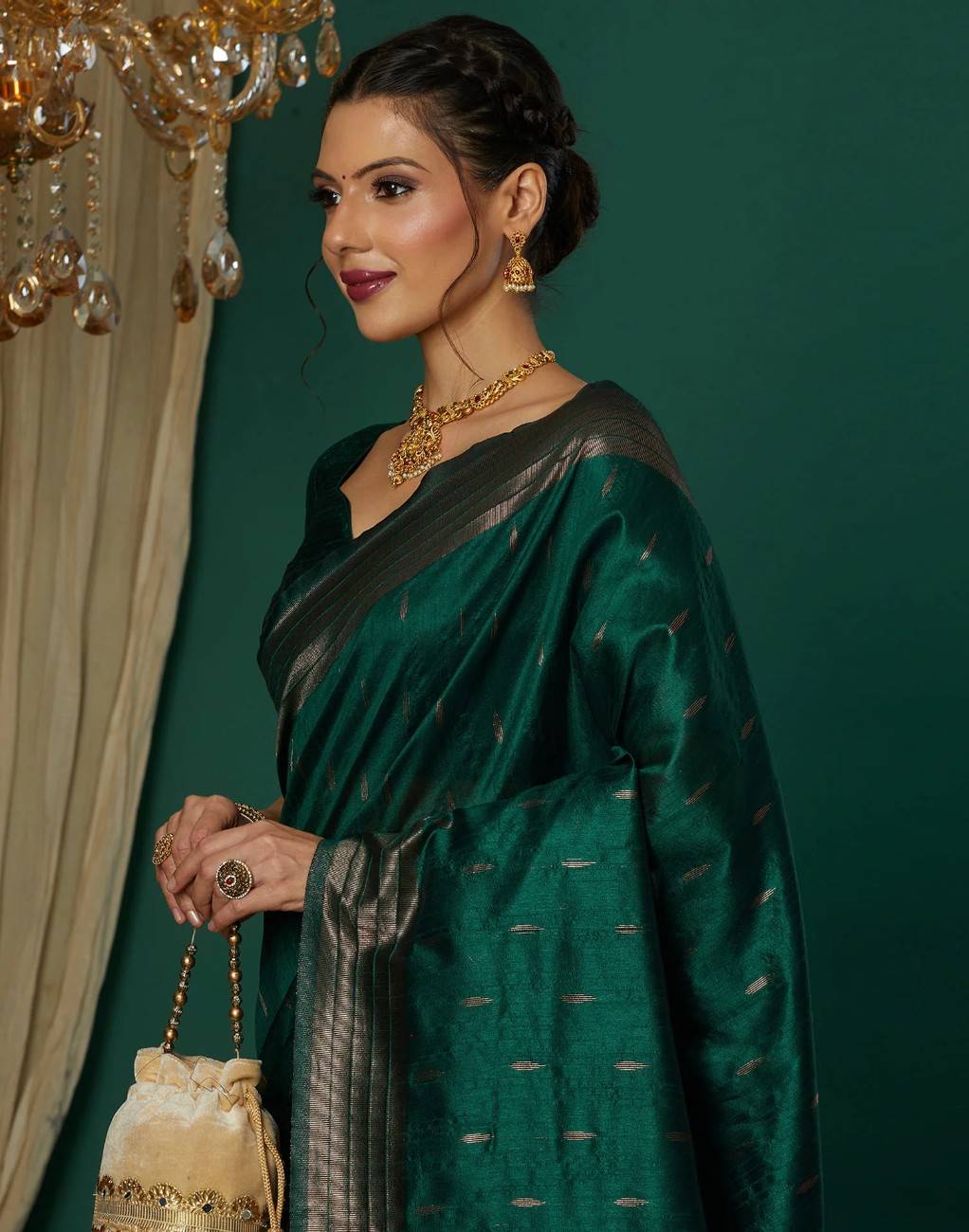 Woman in a green saree with gold jewelry against a dark green background