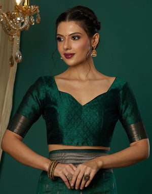 Woman wearing a green blouse with black sleeves against a dark green background