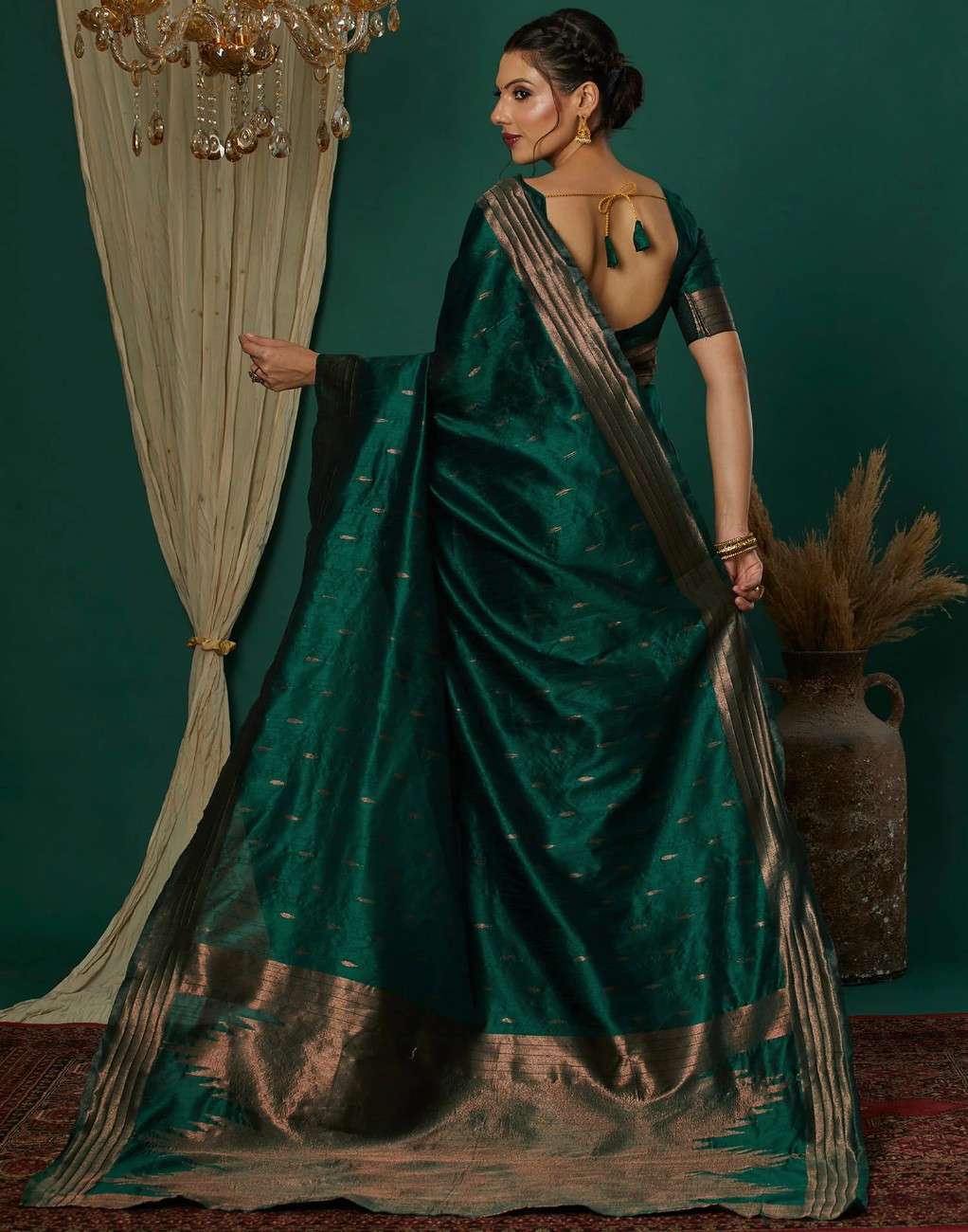 Woman in a green saree with gold details against a dark green background