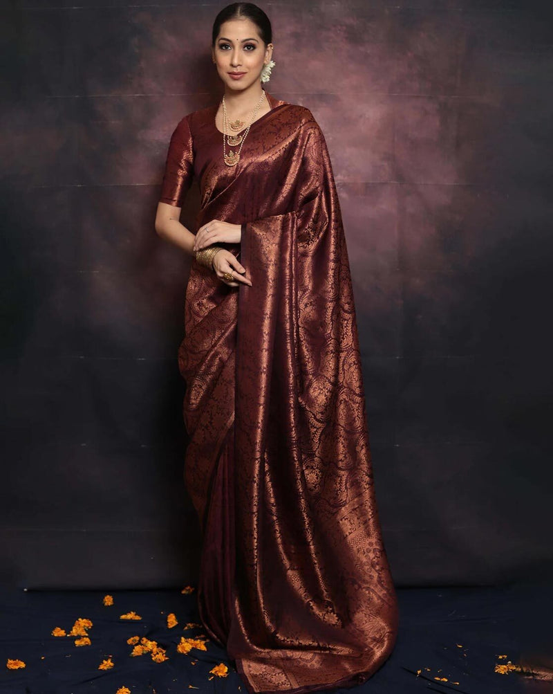 Woman wearing a maroon saree against a dark background