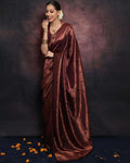 Woman in a maroon saree with jewelry against a dark background