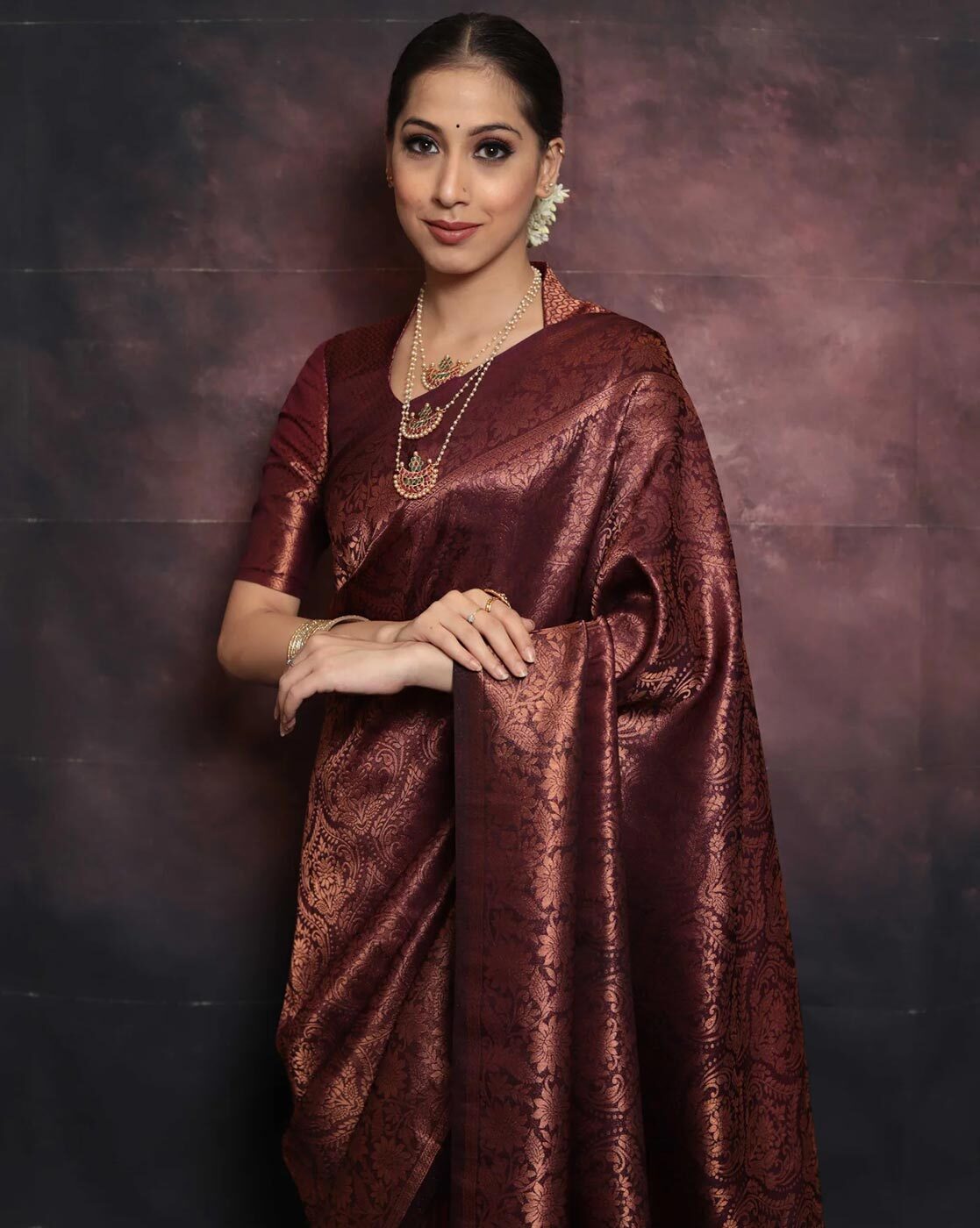 Woman wearing a maroon saree with a dark background