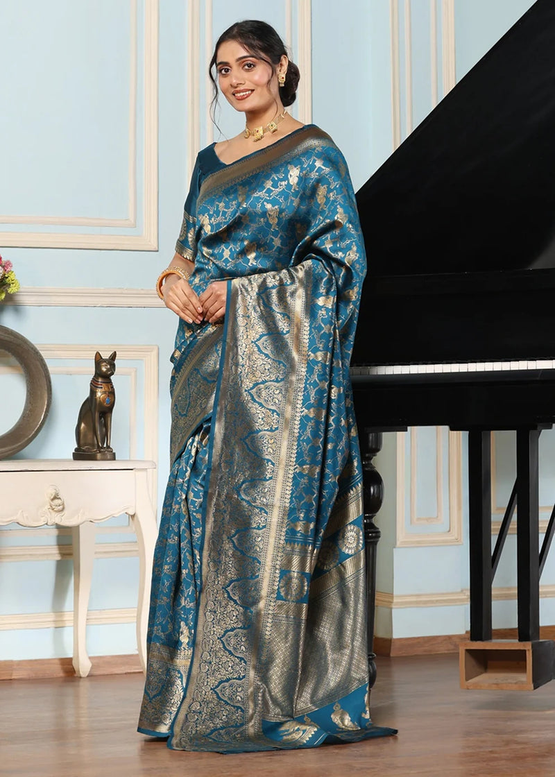 Woman in a blue saree standing next to a piano in an elegant room.