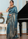 Woman wearing a blue and silver saree in a room with a piano.