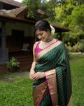 Woman in a green saree with a pink blouse standing outdoors.