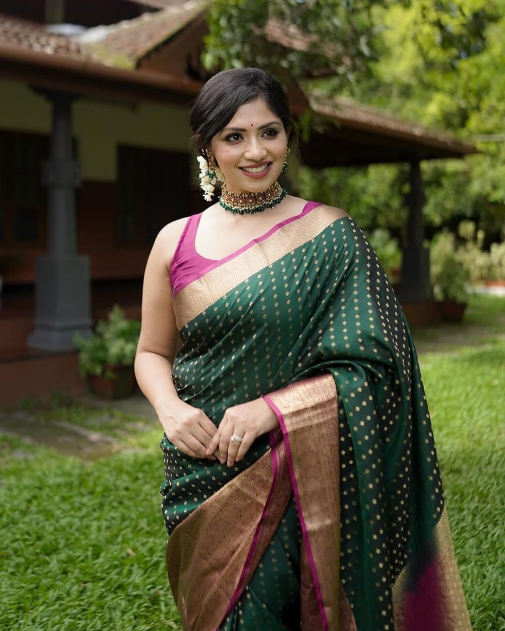 Woman in a green saree with a pink blouse standing outdoors.