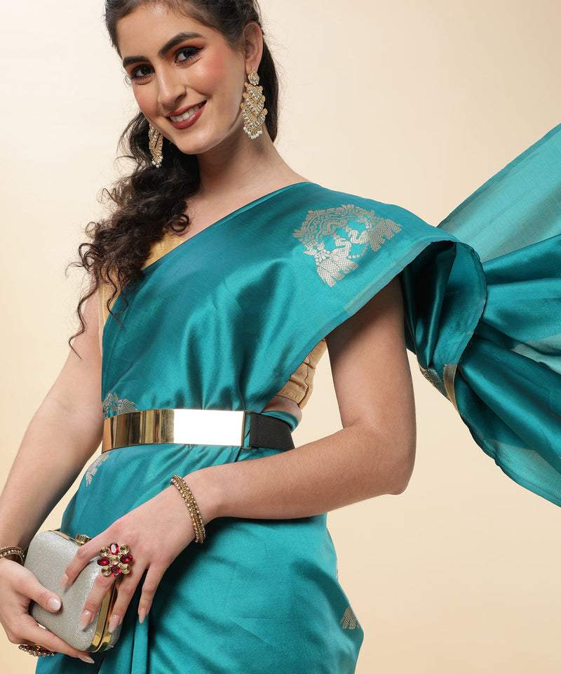 Woman wearing a teal saree with gold border on a beige background