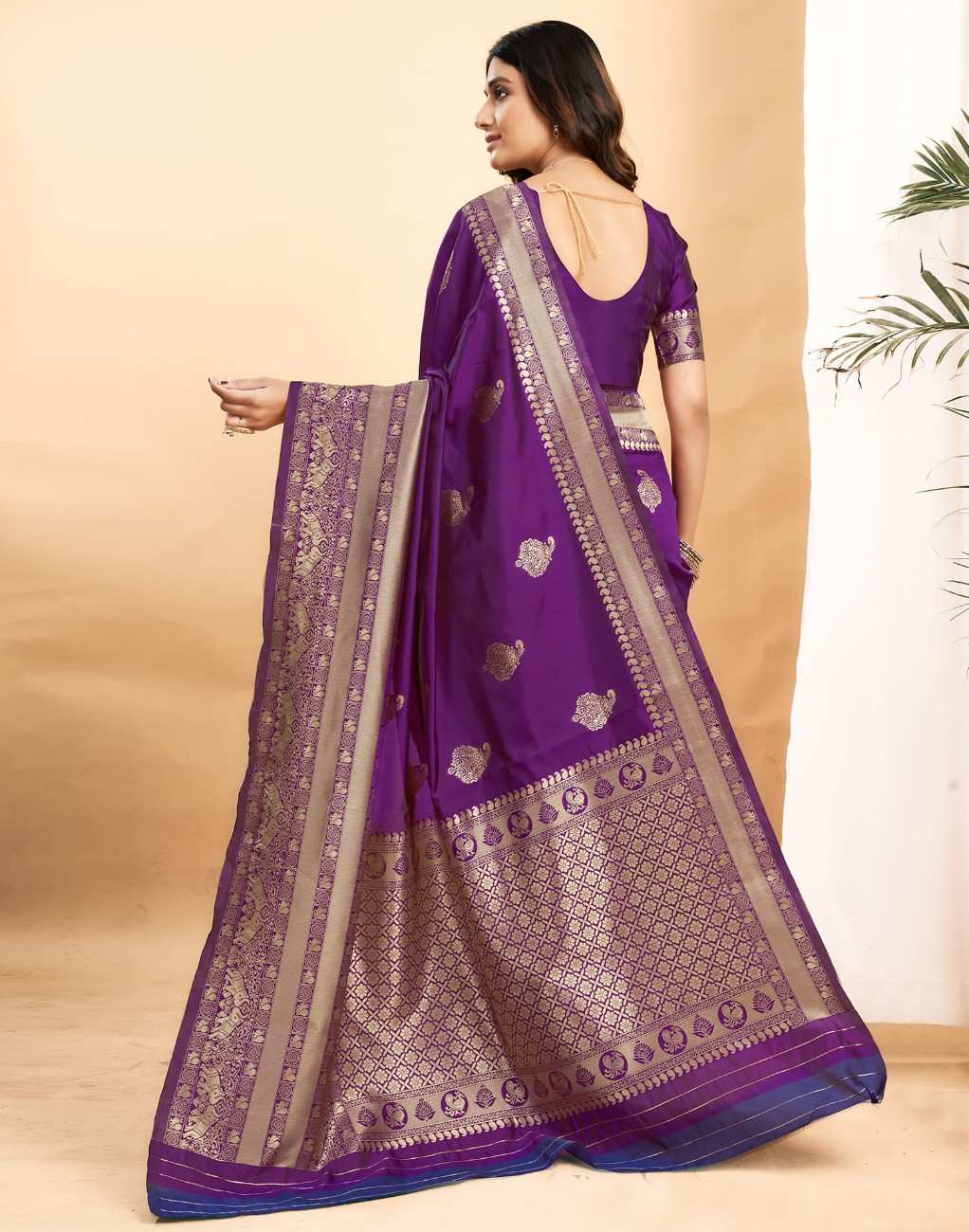 Woman wearing a purple saree with gold patterns on a beige background