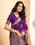 Woman wearing a purple saree with silver patterns on a beige background