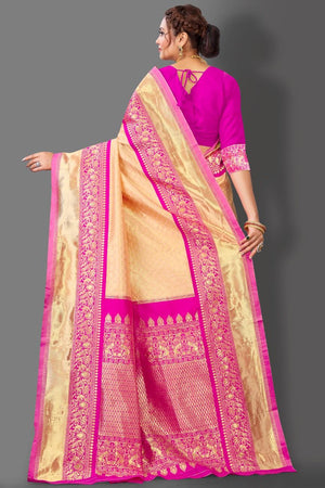 Woman wearing a pink and beige saree with intricate patterns on a gray background