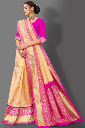 Woman wearing a beige and pink saree with a gray background